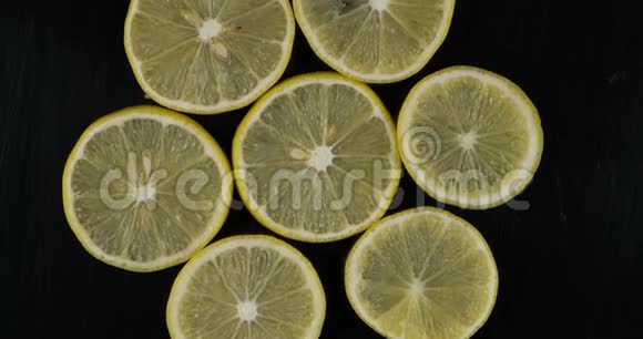 在黑色背景下收集新鲜柠檬片旋转柑橘果实上景视频的预览图