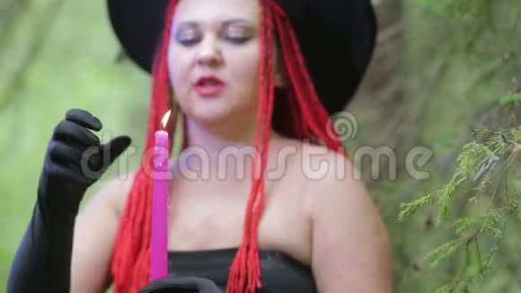 一个红头发戴着黑帽子的年轻女巫在森林里施展魔法视频的预览图