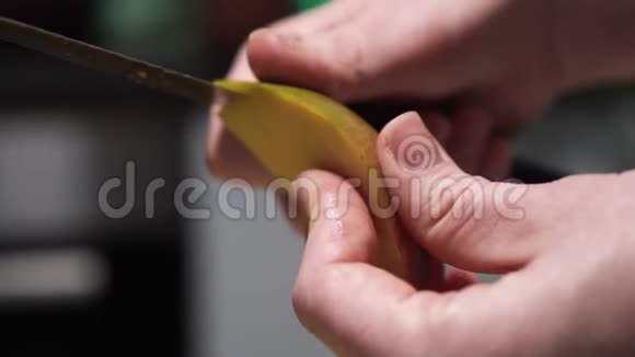 女孩剥芒果女人她的手用刀切芒果的皮视频的预览图
