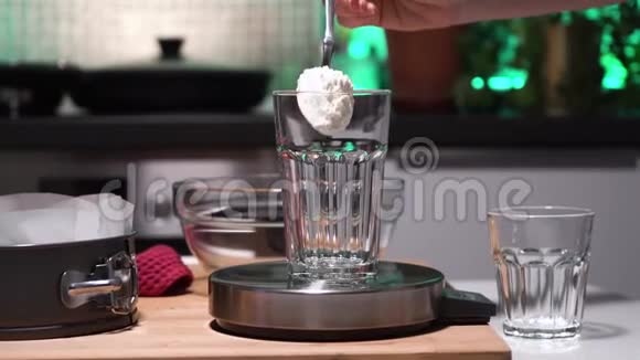 鳞片上的透明玻璃女孩或女人用手把杯子倒在天平上厨房里有白面粉视频的预览图