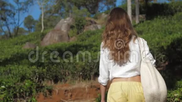 带着袋子走过公园的女孩在绿色斜坡上慢动作视频的预览图