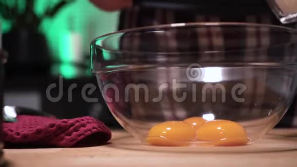 女孩用三个蛋黄把糖倒入透明的碗里做美味的蛋糕视频的预览图