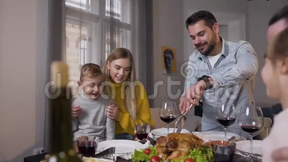 在感恩节庆祝活动中一家人闲着开心地笑着爸爸切传统的烤火鸡视频的预览图