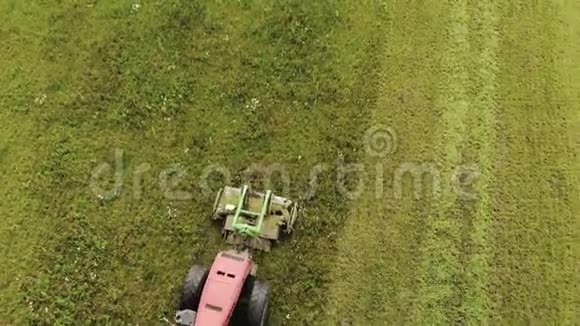 农民在一辆红色拖拉机和一台联合安装的割草机与圆盘旋转刀割草成青贮饲料牲畜视频的预览图