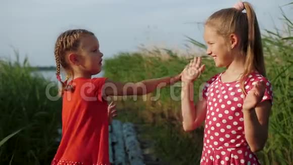两个可爱的小女孩在湖边玩蛋糕游戏视频的预览图