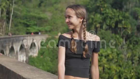 女人坐在著名的桥上享受狂野的热带自然视频的预览图