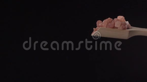 粉红喜马拉雅盐是从一个木勺从上到下在黑色背景上缓慢地流动而成视频的预览图