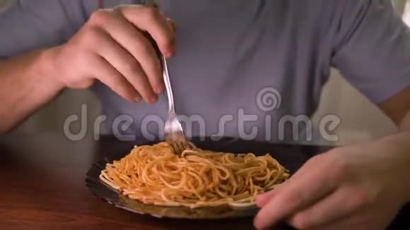 一个男人把意大利面和番茄酱混合在黑色盘子里特写视频的预览图