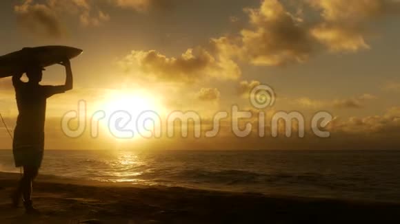 冲浪情侣在海滩上日落时分带着长长的冲浪板走着视频的预览图