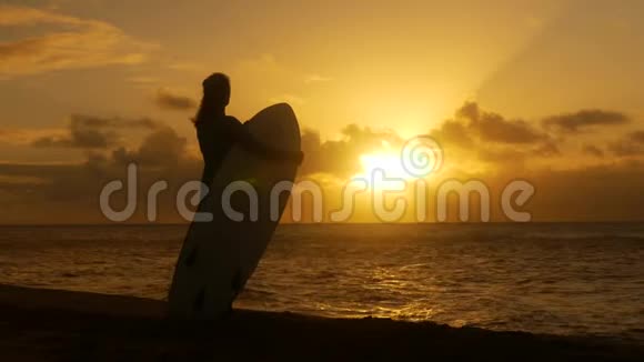 年轻女孩在海滩冲浪等待日落时完美的海浪视频的预览图