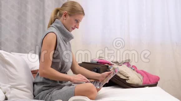 一位女士坐在床上用笔记本电脑上的银行卡在线支付机票视频的预览图