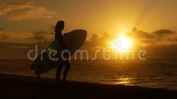 年轻女孩在海滩冲浪等待日落时完美的海浪视频的预览图