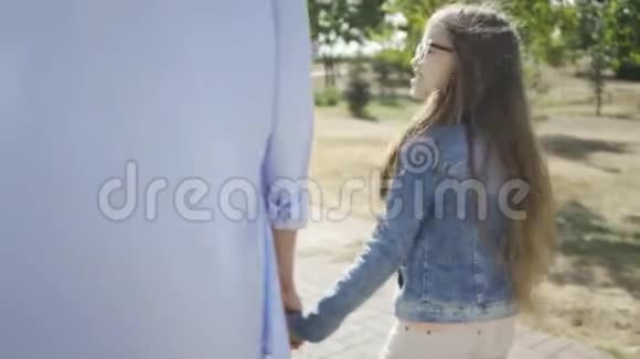 在城市的背景下哥哥牵着妹妹的手在公园里散步视频的预览图