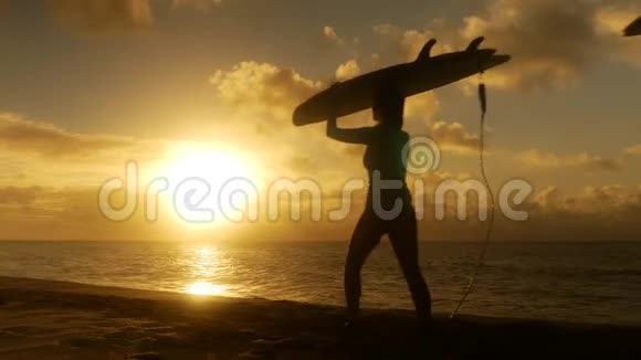 冲浪情侣在海滩上日落时分带着长长的冲浪板走着视频的预览图