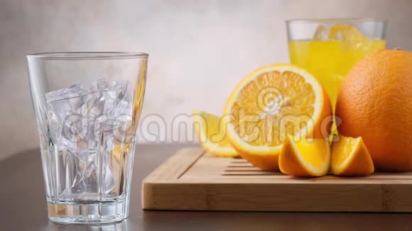 将橙汁倒入杯中在背景新鲜橙果上加入冰块视频的预览图