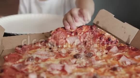 4岁的可爱男孩穿着一件白色t恤把一大块开胃菜的肉披萨放在盘子里看上去视频的预览图