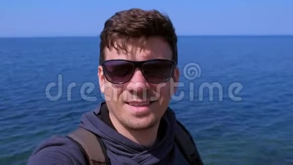 男人视频聊天自拍智能手机在海边海浪手问候和微笑视频的预览图
