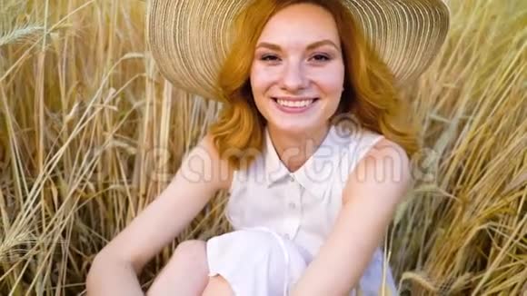 可爱的女孩戴着大草帽坐在麦田里视频的预览图