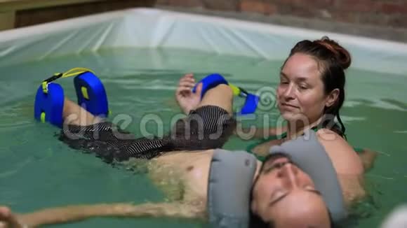 为泳池里的男人做腿部按摩的治疗师视频的预览图