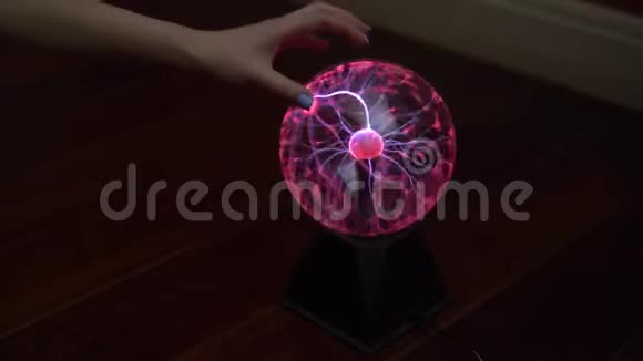 一只雌性的手触摸一个等离子球发出小闪电在黑暗中用电做实验视频的预览图