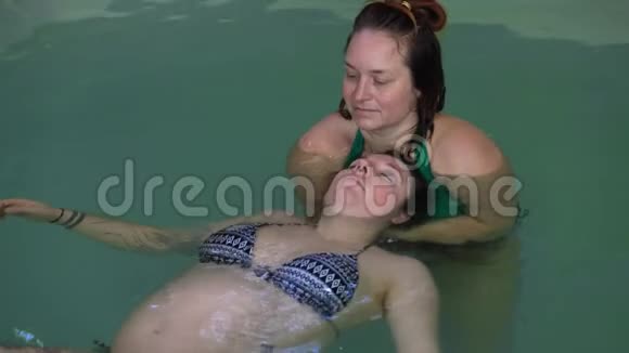 有教练的孕妇在游泳池放松视频的预览图