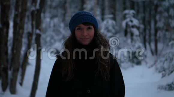 微笑的女人独自站在雪地里玩视频的预览图