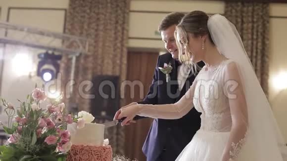 新娘和新郎正在切婚礼蛋糕新婚夫妇切块蛋糕视频的预览图