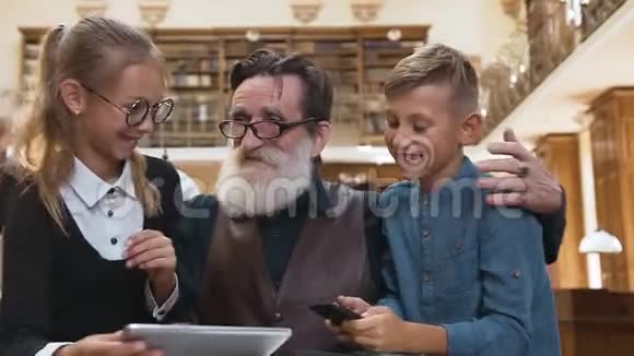 快乐的祖父和孙子们一起愉快地在图书馆度过他们的时光视频的预览图