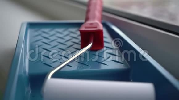 一个红色手柄的小泡沫滚筒躺在蓝色托盘里准备绘画视频的预览图