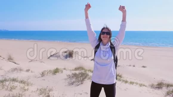 快乐的女孩举起双臂在海边沙滩上度假的赢家概念视频的预览图