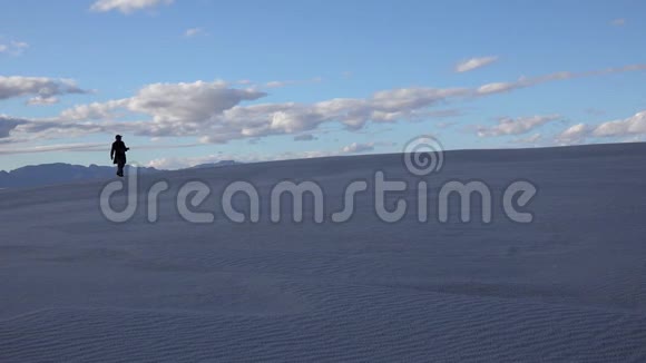 人们在白云背景下的沙漠景观中在白色石膏砂上行走白沙国家沙丘视频的预览图