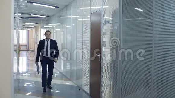穿着黑色西装的白人商人沿着走廊走到他的办公室视频的预览图
