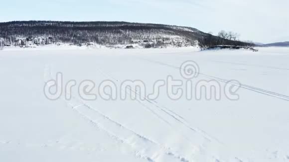 瑞典无人驾驶飞机在阳光明媚的冬日飞越冰冻的湖泊和小岛屿在瑞典北部有小山桦视频的预览图