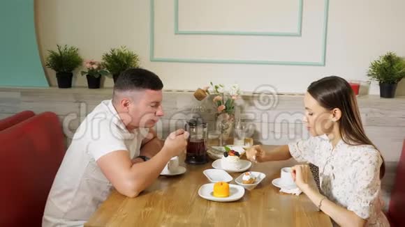 可爱的一对夫妇在糖果店的餐桌上吃天然蛋糕视频的预览图