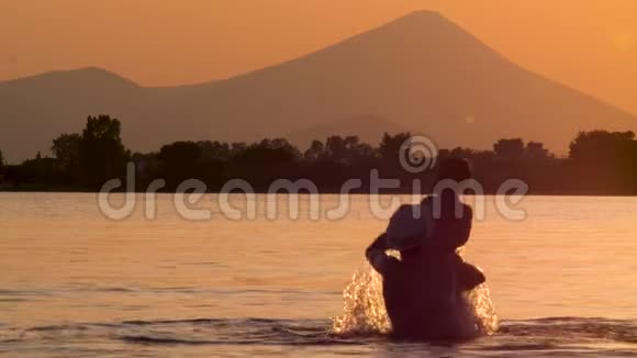 父子在水中玩海在黄昏的背景下快乐的父亲花时间和孩子在海里视频的预览图