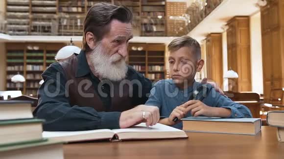 正面看美丽的胡须男向他十几岁的孙子解释读书的重要性视频的预览图