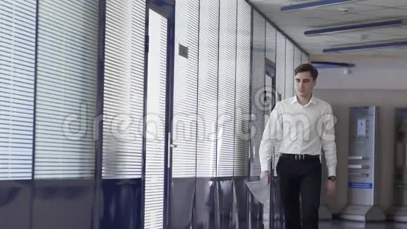 慢动作的人在一栋正在施工的办公楼里走下一条白色的玻璃走廊视频的预览图