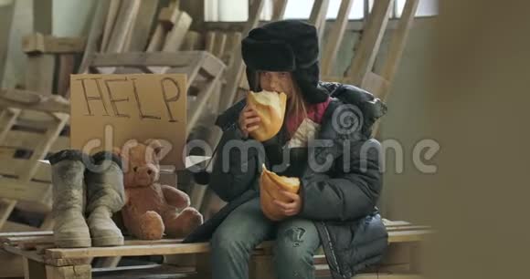一个无家可归的女孩的肖像肮脏的脸贪婪地吃着面包饥饿孤独的难民坐在视频的预览图