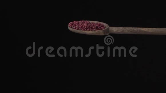 在黑色的背景上红色的胡椒从木勺慢慢地倒到底部视频的预览图