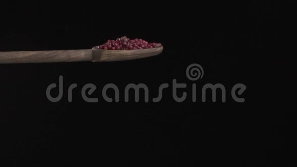 在黑色背景下红色的胡椒粉从木勺中缓慢地倒入底部视频的预览图