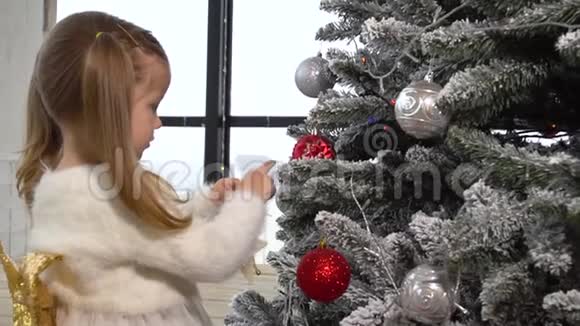 可爱的女孩用玩具装饰圣诞树视频的预览图