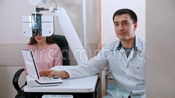 橱柜里的眼科治疗年轻的微笑妇女在一台带有验光设备的视力检查视频的预览图