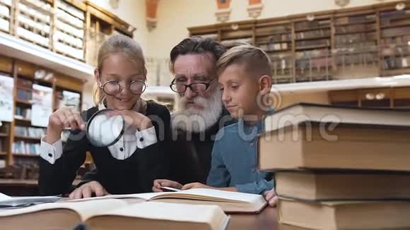 快乐的老胡子爷爷在图书馆里给他那微笑的十几岁的孙子们读了一本令人兴奋的书视频的预览图