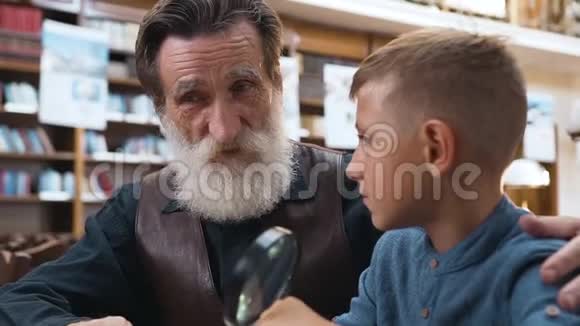 漂亮的小男孩仔细地听着他尊敬的祖父讲书视频的预览图