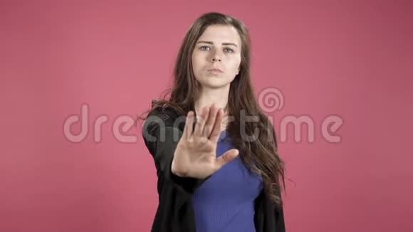 年轻的商务女性在粉红色背景下显示停止标志否认拒绝不同意视频的预览图