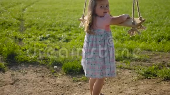 3岁的小女孩试图爬上一个木绳秋千视频的预览图