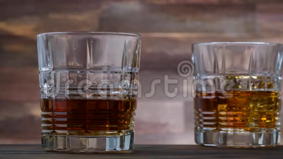 冰块掉在玻璃杯里洒着金色威士忌和酒精视频的预览图