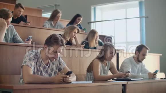 大量的学生看着智能手机的屏幕在现实生活中不交流只写信息视频的预览图