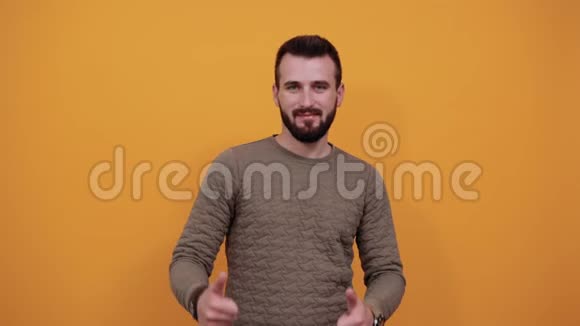 性格开朗的男人在孤立的橙色背景下竖起大拇指面带微笑视频的预览图