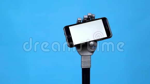 一只机械手拿着一个白色屏幕的手机灰色半机人手拿着蓝色背景的智能手机视频的预览图